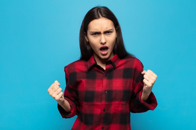 Photo young hispanic woman shouting aggressively with an angry expression or with fists clenched celebrating success