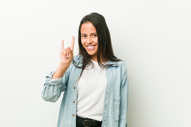 Young hispanic woman showing a horns gesture