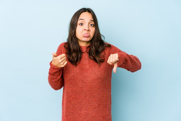 Young hispanic woman showing thumbs up and thumbs down