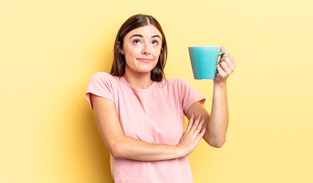 Young hispanic woman shrugging, feeling confused and uncertain. coffee cup concept