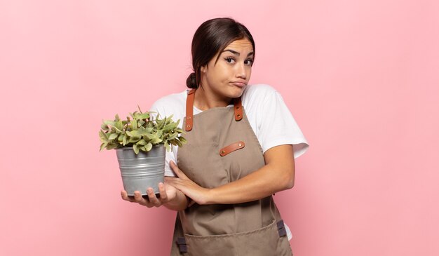 Young hispanic woman shrugging, feeling confused and uncertain, doubting with arms crossed and puzzled look