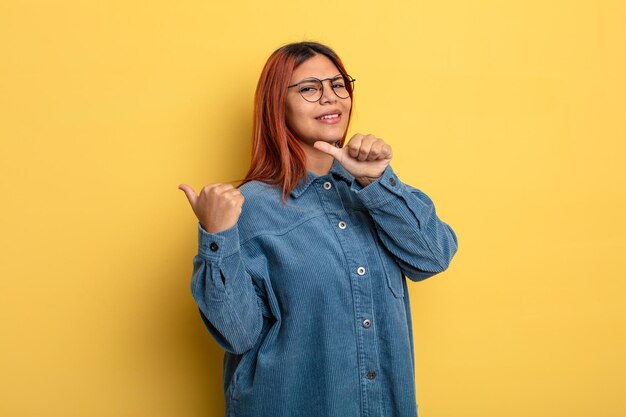 陽気でさりげなく笑顔の若いヒスパニック系女性は、幸せと満足を感じて、側面のコピースペースを指しています