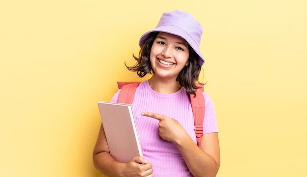 Young hispanic woman smiling cheerfully, feeling happy and pointing to the side. back to school concept
