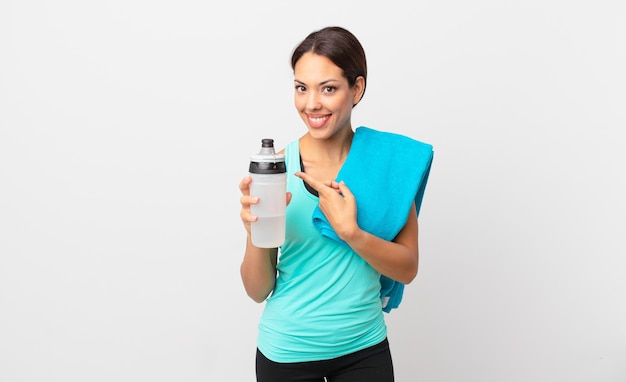 Young hispanic woman smiling cheerfully, feeling happy and pointing to the side. fitness concept