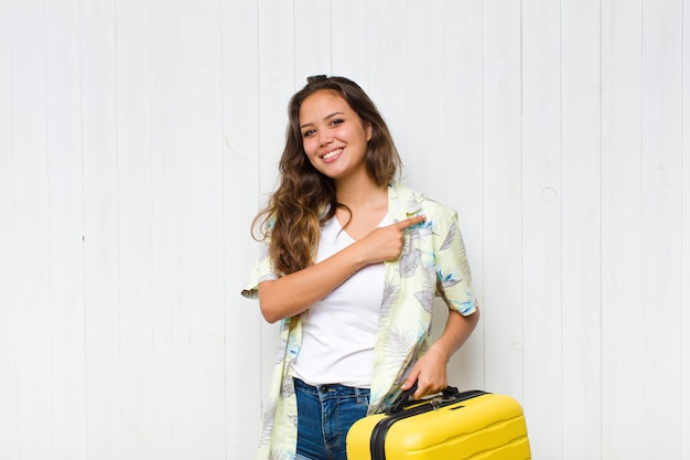 Young hispanic woman smiling cheerfully, feeling happy and pointing to the side and upwards, showing object in copy space