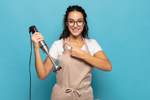 Young hispanic woman smiling cheerfully, feeling happy and pointing to the side and upwards, showing object in copy space