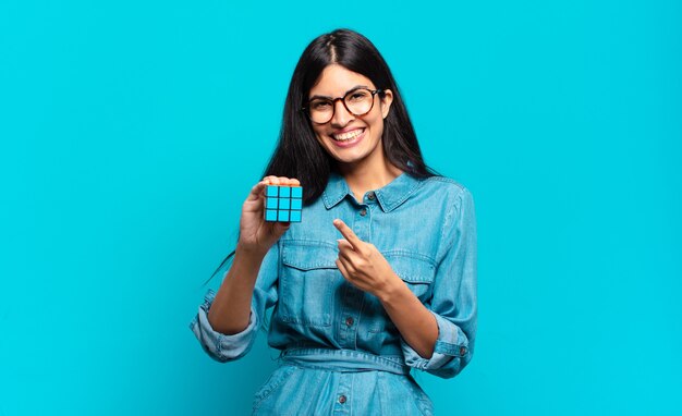 Young hispanic woman smiling cheerfully, feeling happy and pointing to the side and upwards, showing object in copy space.