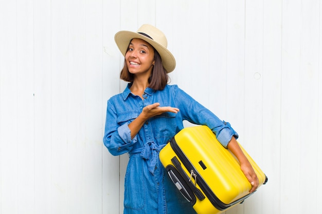 Young hispanic woman smiling cheerfully, feeling happy and showing a concept in copy space with palm of hand