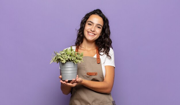 Young hispanic woman smiling cheerfully, feeling happy and showing a concept in copy space with palm of hand