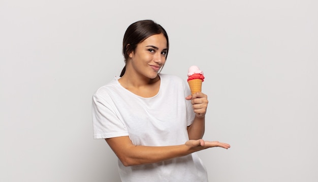 Young hispanic woman smiling cheerfully, feeling happy and showing a concept in copy space with palm of hand