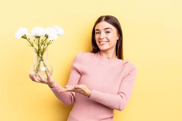 Young hispanic woman smiling cheerfully, feeling happy and showing a concept. flower pot concept