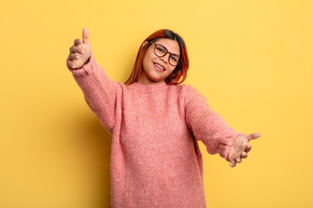 Young hispanic woman smiling cheerfully giving a warm, friendly, loving welcome hug, feeling happy and adorable