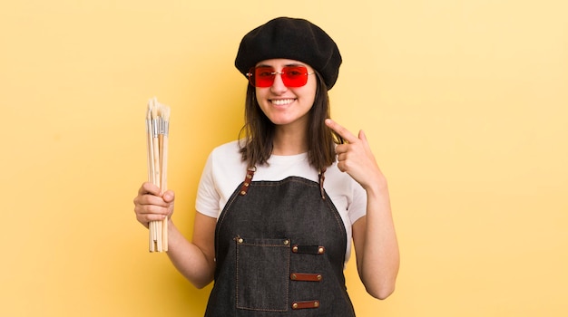 Young hispanic woman smiling confidently pointing to own broad smile artist concept