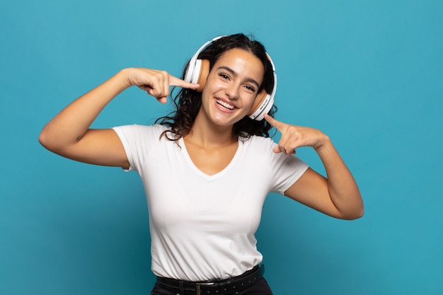 Young hispanic woman smiling confidently pointing to own broad smile, positive, relaxed, satisfied attitude