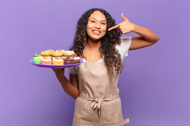 Young hispanic woman smiling confidently pointing to own broad smile, positive, relaxed, satisfied attitude