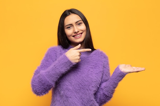 Young hispanic woman smiling, feeling happy, carefree and satisfied, pointing to concept