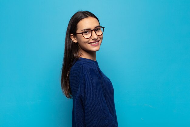 Young hispanic woman smiling gleefully, feeling happy, satisfied and relaxed, with crossed arms and looking to the side