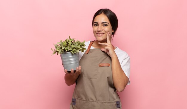 Young hispanic woman smiling happily and daydreaming or doubting, looking to the side