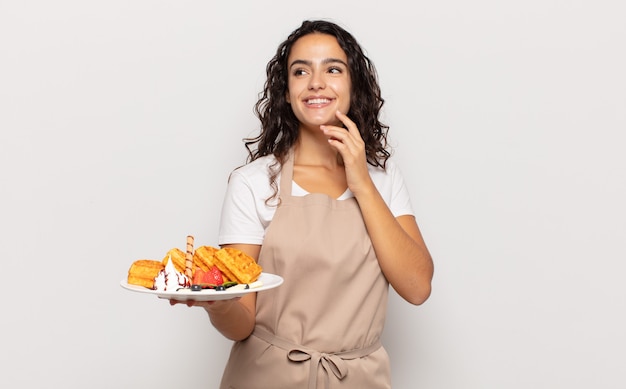 Young hispanic woman smiling happily and daydreaming or doubting, looking to the side