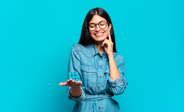 Young hispanic woman smiling happily and daydreaming or doubting