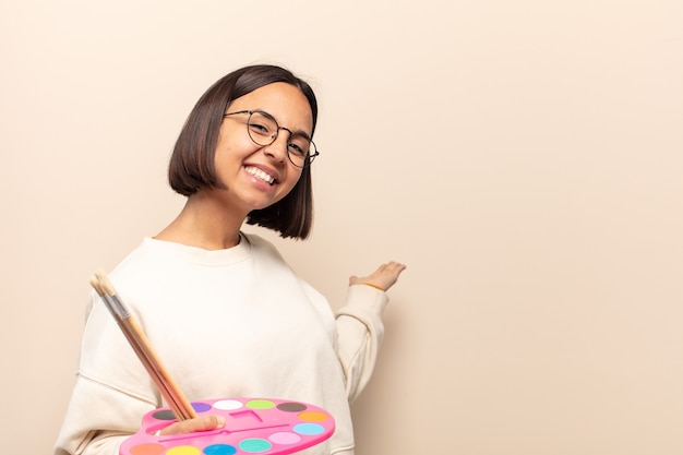 Young hispanic woman smiling happily and looking sideways, wondering, thinking or having an idea