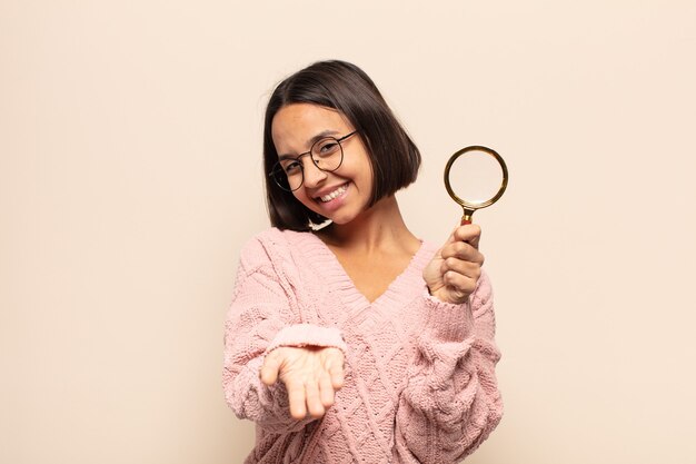 Young hispanic woman smiling happily with friendly, confident, positive look, offering and showing an object or concept