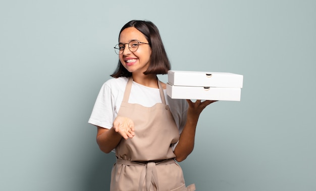 Young hispanic woman smiling happily with friendly, confident, positive look, offering and showing an object or concept