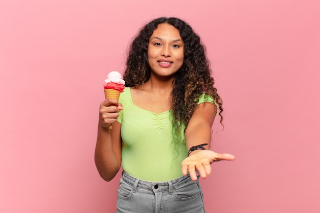 Young hispanic woman smiling happily with friendly, confident, positive look, offering and showing an object or concept