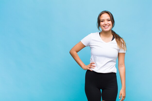 Young hispanic woman smiling happily with a hand on hip and confident, positive, proud and friendly attitude