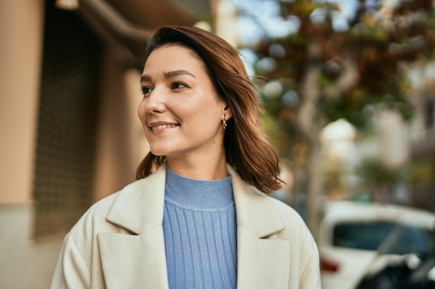 若いヒスパニック系の女性が街に立って幸せに微笑んでいる