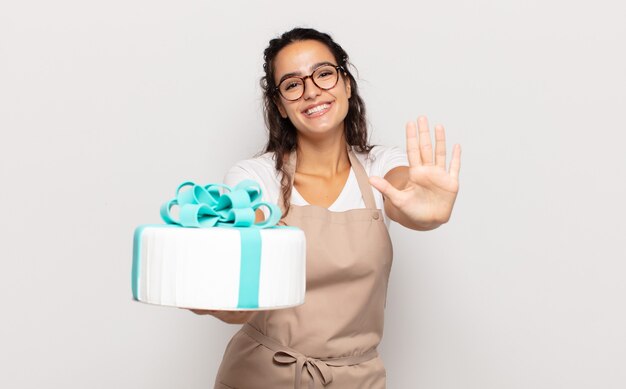 Young hispanic woman smiling and looking friendly, showing number five or fifth with hand forward, counting down