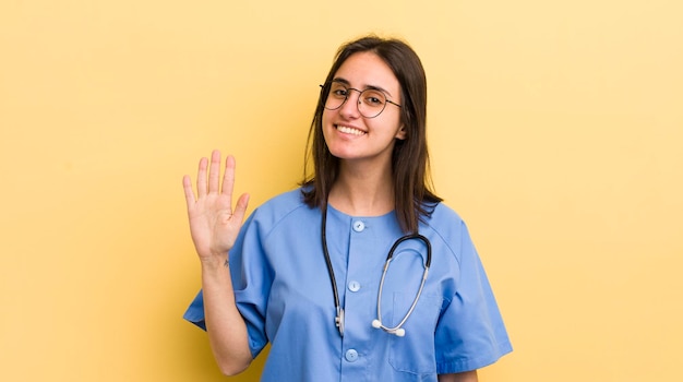 Молодая латиноамериканка улыбается и выглядит дружелюбно, показывая концепцию медсестры номер пять