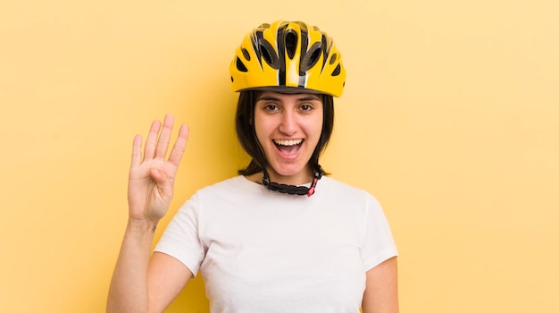 Young hispanic woman smiling and looking friendly showing number four bike helmet concept