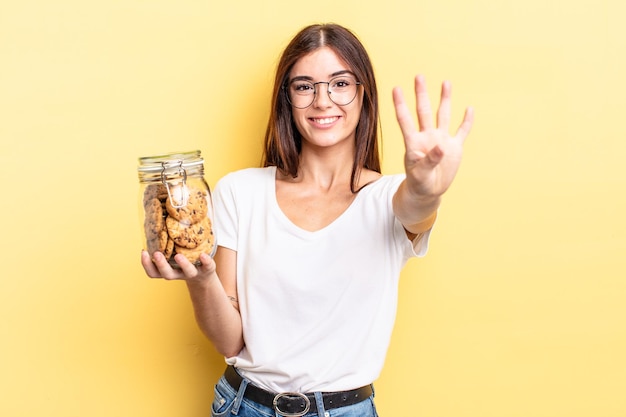 Young hispanic woman smiling and looking friendly, showing number four. cookies bottle concept