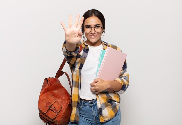 Young hispanic woman smiling and looking friendly, showing number four or fourth with hand forward, counting down