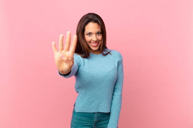 Young hispanic woman smiling and looking friendly, showing number four