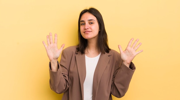 Foto giovane donna ispanica che sorride e che sembra amichevole che mostra il numero dieci o decimo con il conto alla rovescia in avanti della mano