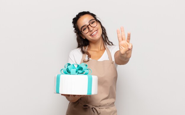 Young hispanic woman smiling and looking friendly, showing number three or third with hand forward, counting down