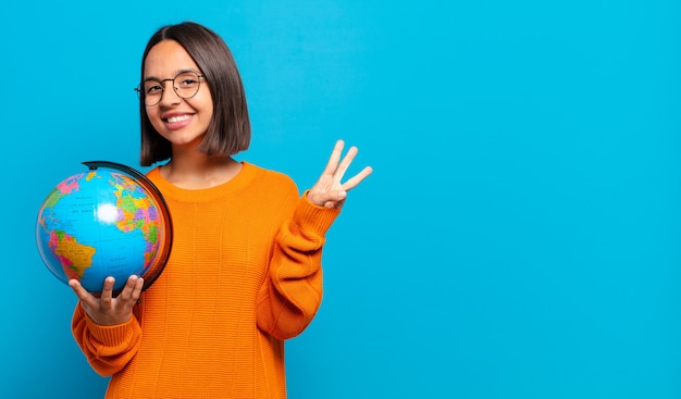 Young hispanic woman smiling and looking friendly, showing number three or third with hand forward, counting down