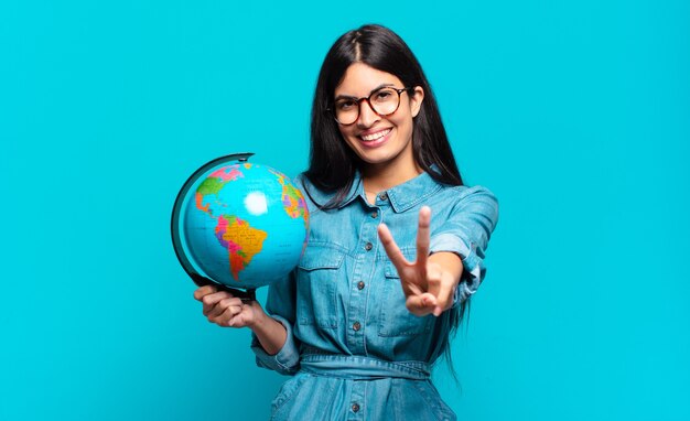 Young hispanic woman smiling and looking friendly, showing number two or second with hand forward, counting down. earth planet concept