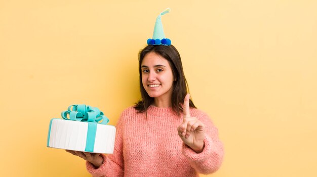 Young hispanic woman smiling proudly and confidently making number one birthday concept