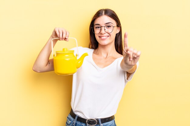 Young hispanic woman smiling proudly and confidently making number one. teapot concept