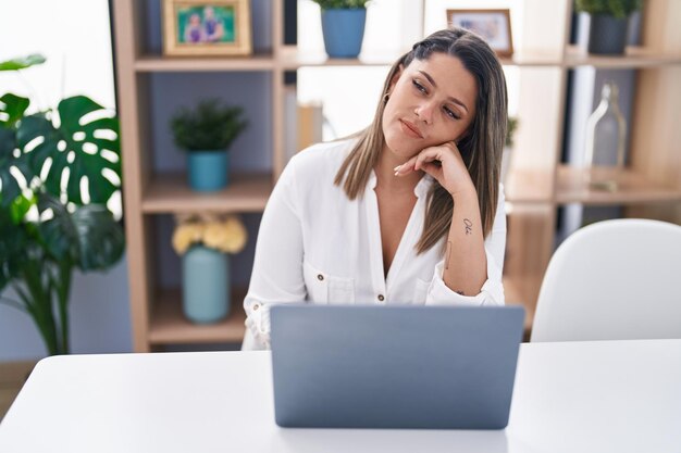 Young hispanic woman using laptop with relaxed expression at home