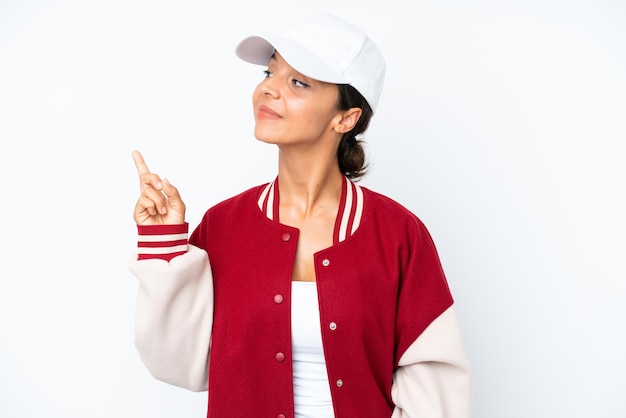 Foto giovane donna ispanica che indossa un'uniforme da baseball isolata su sfondo bianco che punta su una grande idea