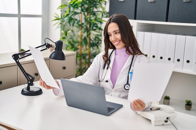 Young hispanic woman wearing doctor uniform working at clinic