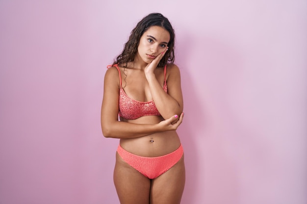 Young hispanic woman wearing lingerie over pink background thinking looking tired and bored with depression problems with crossed arms