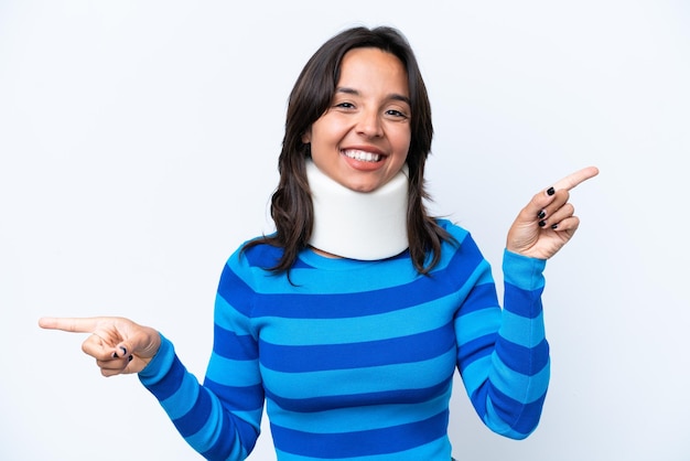 Young hispanic woman wearing neck brace isolated on white background pointing finger to the laterals and happy