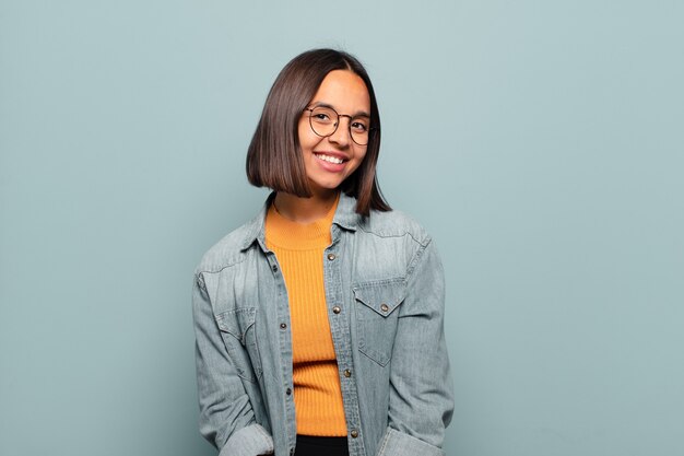 Young hispanic woman with a big, friendly, carefree smile, looking positive, relaxed and happy, chilling