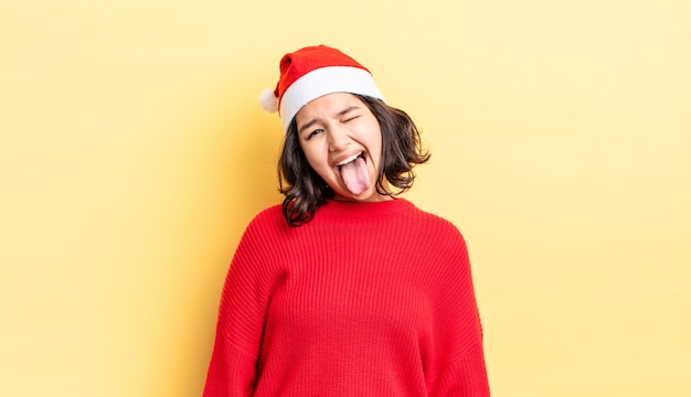 Молодая латиноамериканская женщина с веселым и бунтарским настроем, шутит и высунула язык. рождественская концепция