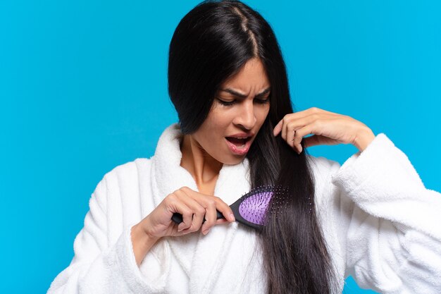 Young hispanic woman with a hair brush.